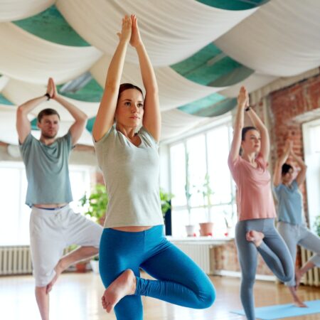 group of people doing yoga tree pose at studio